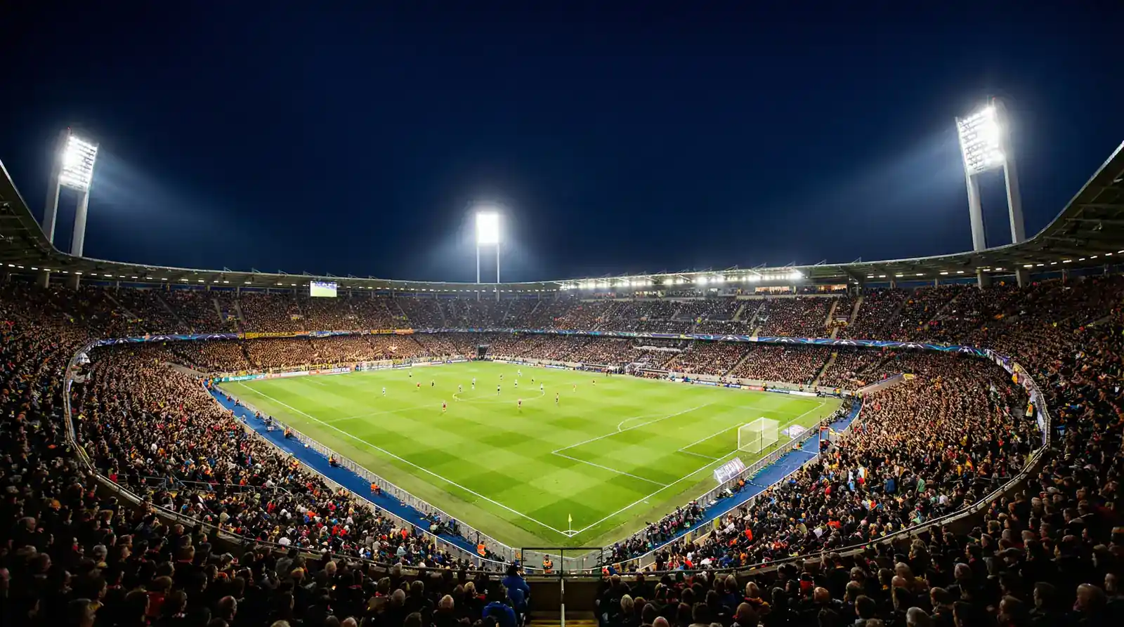 Vue panoramique d'un stade de football éclairé la nuit pendant un match avec les projecteurs illuminant la pelouse verte