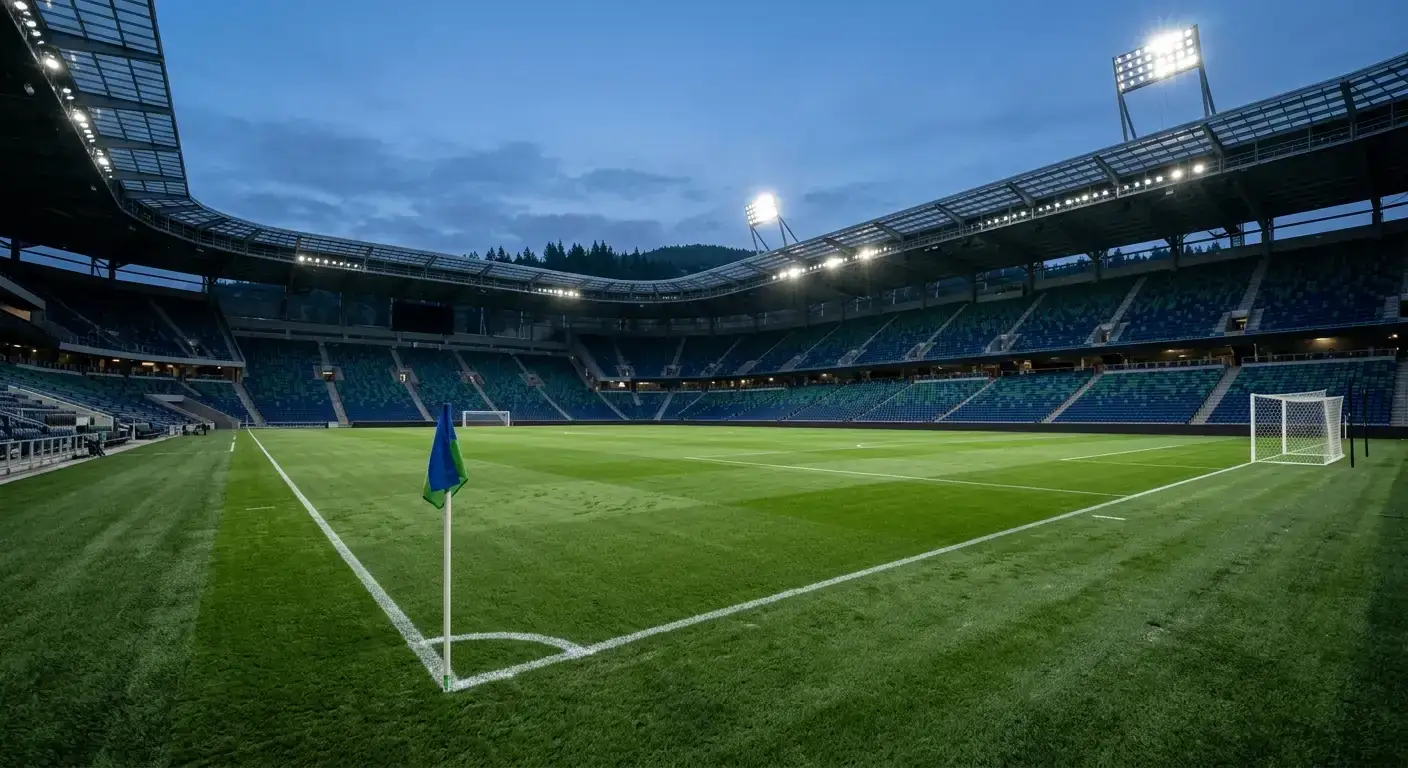 Stade de football moderne vu de l'intérieur au crépuscule, tribunes vides, pelouse éclairée par les projecteurs